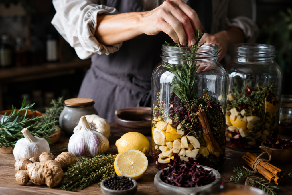 ai image of a dainty hand filling a large wide mouth glass jar with fire cider ingredients